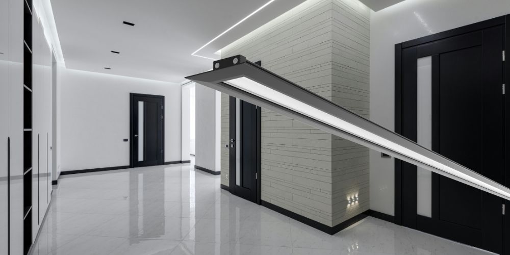 Modern hallway with black doors and recessed LED lighting, featuring a linear LED luminaire.