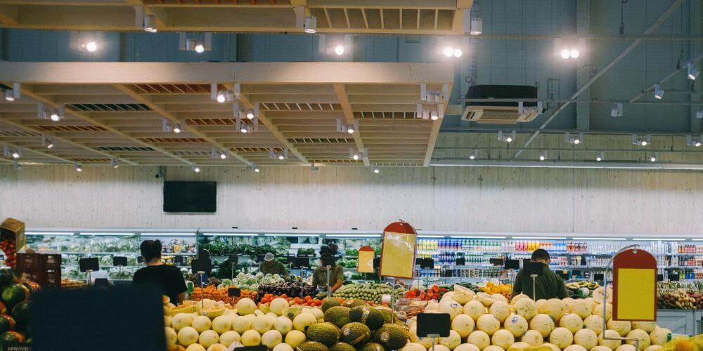 Zone de fruits et légumes dans un supermarché éclairée par des projecteurs sur rail